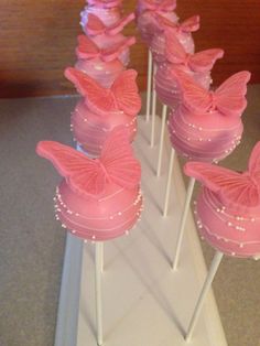 there are many pink cupcakes on sticks with bows and pearls around them in the shape of shoes