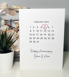 a card with a heart on it next to a potted plant and seashells