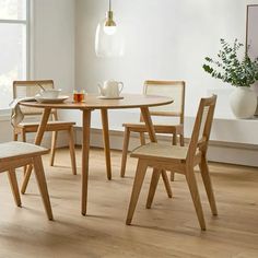 a wooden table with chairs around it in a room next to a potted plant