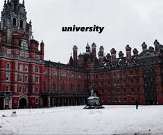 a large red building with a clock tower in front of it and snow on the ground