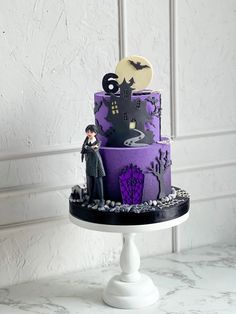 a purple and black cake with a figurine on top