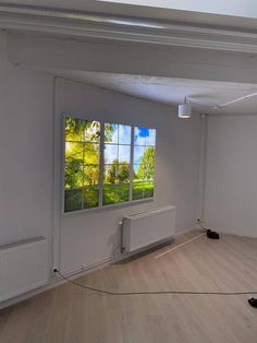 an empty room with large windows and hard wood flooring in the center, on which there is a radiator