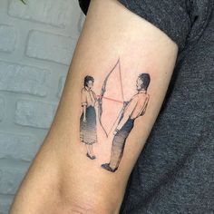 a man and woman holding an arrow tattoo on the arm