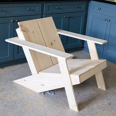 a wooden chair sitting on top of a kitchen floor next to blue cabinets and drawers