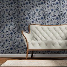 a white couch sitting in front of a blue floral wallpaper