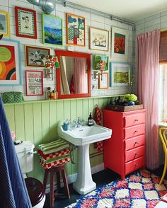 a bathroom with pictures on the wall and a sink in the middle, next to a window