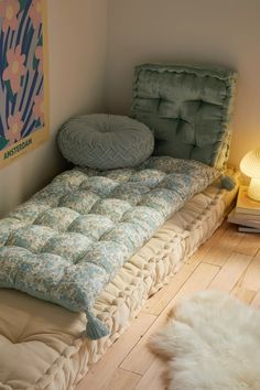 a bed sitting on top of a wooden floor next to a lamp