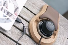 an electronic device is sitting on top of a wooden table next to a book and headphones