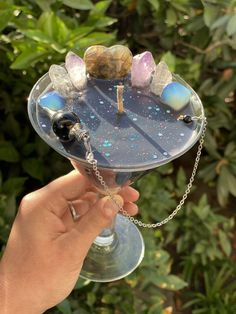 a person holding up a wine glass with rocks on the rim and chain around it