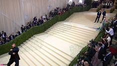 a man is walking down the stairs in front of an audience at a fashion show