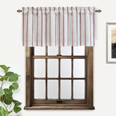 a window with a striped valance hanging on the wall next to a potted plant