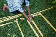 a person kneeling on the ground next to some bamboo poles and sticks with holes in them