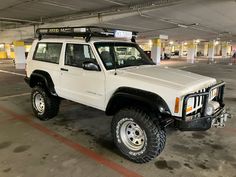 a white jeep is parked in an empty parking garage with no one around it,