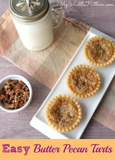 three pecan pies on a plate next to a bowl of nuts and a glass of milk