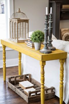 a yellow table with two candles on it and some books sitting on top of it