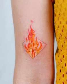 a woman's arm with a small fire tattoo on the left side of her arm