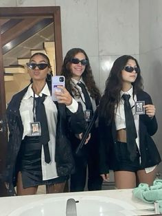 three women in black and white outfits are taking a selfie