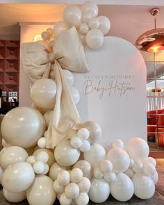 white balloons and bows are on display at the entrance to a baby's first birthday party