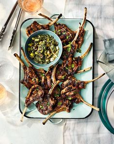 a platter with skewered lamb chops and a bowl of salsa