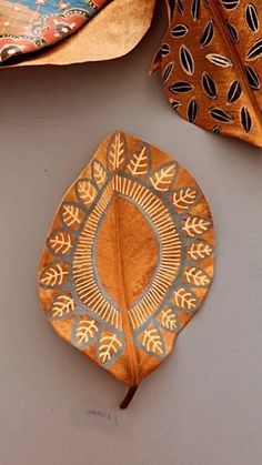 two wooden plates with designs on them sitting next to each other and one has a decorative leaf design