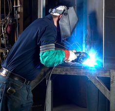 a welder working on a piece of metal with blue light coming from his hands