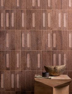 a table with a bowl on top of it in front of a wall that has squares and rectangles