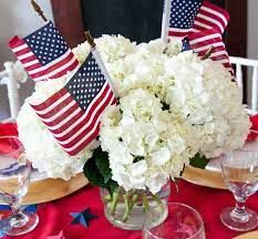 a vase filled with white flowers sitting on top of a red table cloth covered table