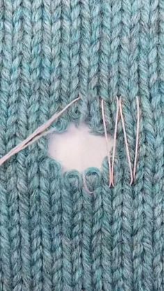 the needles are next to the hole in the knitted material that has been stitched together