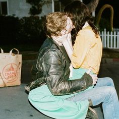 two people are sitting on a bench and one is holding the other's head