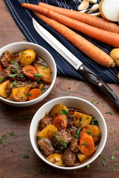 two white bowls filled with stew next to carrots and onions on a wooden table