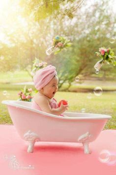 a baby sitting in a pink bath tub