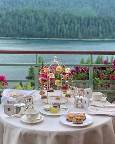 a table with food and drinks on top of it near the water's edge