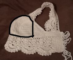 a white crocheted bag with black trim on it sitting on a brown blanket