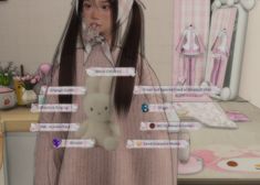 a girl with long hair standing in front of a computer screen holding a teddy bear