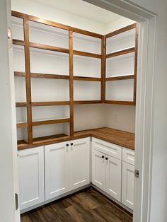 a kitchen with white cabinets and wood flooring on the side walk - in closet