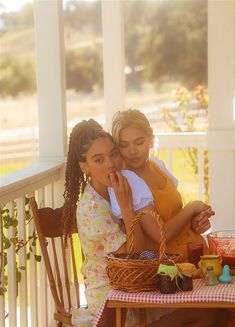 two women sitting at a table on the porch