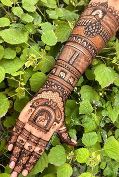 a person's hand with henna tattoos on it and green leaves in the background