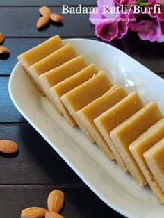 several pieces of food on a white plate with almonds around it and flowers in the background