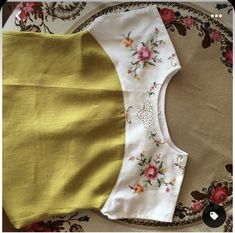 a yellow and white top with flowers on it sitting on a floral print table cloth