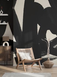 a black and white abstract painting on the wall next to a chair with a vase