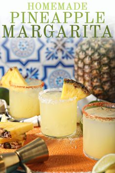 two glasses filled with pineapple margaritas sitting on top of a table next to other drinks