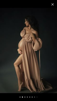 a pregnant woman in a long dress poses for the camera with her legs spread out