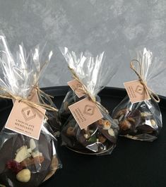 three bags of chocolate covered with nuts on top of a black tray next to each other