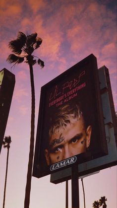 a billboard with a man's face on it and palm trees in the background