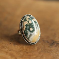 What a great, Ocean Jasper statement ring. It looks and feels like it could have been made by a master silversmith from another time and place. Simple, classic design with the .925 Sterling Silver twist wire and double round split shank. Makes you feel like you're sliding on something that someone will still wear in 50 years. You might want to make room on your hand -- you're going to want to wear this big statement ring all the time. 18X25mm oval cabochon of stunning quality Ocean Jasper All Me Silversmith Rings, Orbit Ring, Big Statement Rings, Opal Drop Earrings, Negative Feelings, Jasper Ring, Jasper Jewelry, Gold And Silver Rings, Detailed Ring