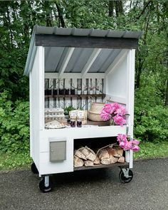 an outdoor food cart with flowers and bottles on it