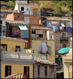 several buildings with clothes hanging from the balconies and an umbrella in front of them