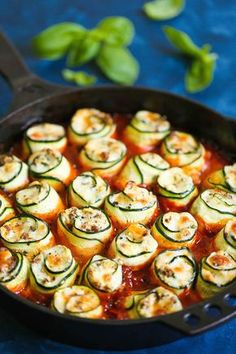 an iron skillet filled with zucchini rolls on top of a blue cloth