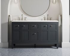 a bathroom vanity with two sinks and a round mirror on the wall above it in an archway