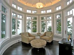 a large living room with high ceilings and round windows on the ceiling is decorated in white